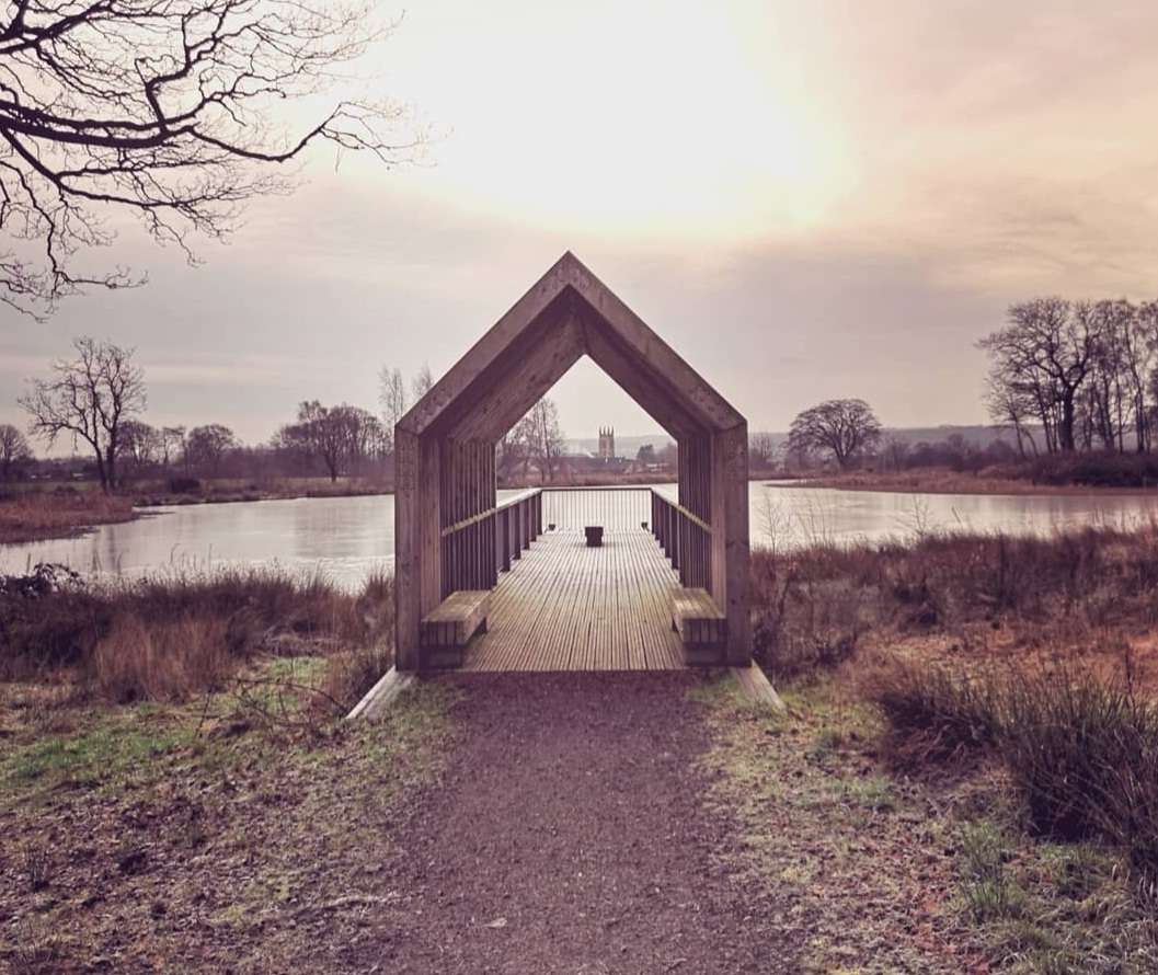 Gravel path leadint to covered wooden walkway which leads to a view over a small loch. Taken on a winters day